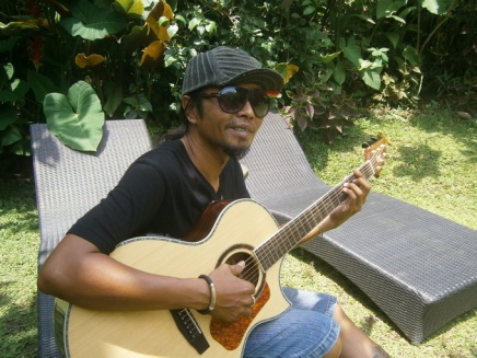 Yaniq playing guitar in the garden